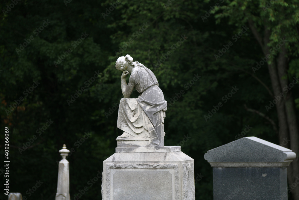 Obraz premium a very old tombstone headpiece statue thinking women angel carved monument marble gravestone in a shadowy graveyard cemetery