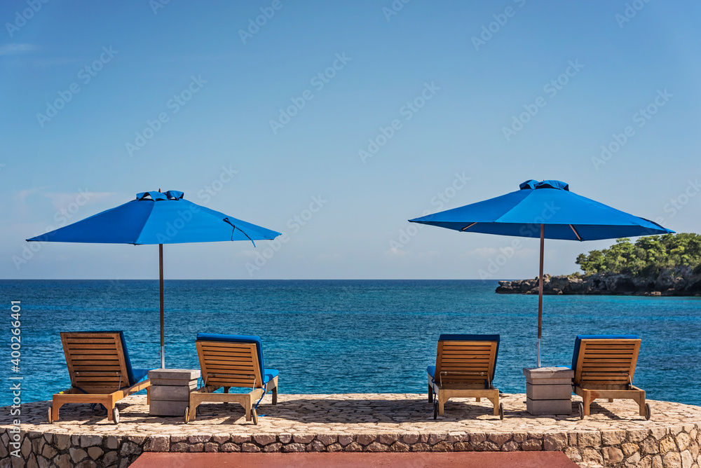 Jamaica, Negril, Beach umbrellas and lounge chairs against tranquil seascape