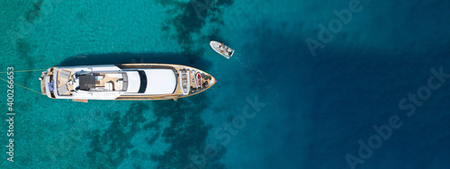 Aerial drone ultra wide top down photo of luxury yacht anchored in tropical exotic bay with emerald crystal clear sea