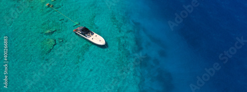 Aerial drone ultra wide photo of speed boat with wooden deck anchored in tropical exotic turquoise crystal clear sea bay