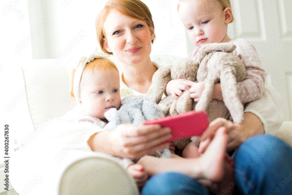 Portrait of mother using smart phone with daughters ( 12-17 months ) Portrait of mother using smart phone with daughters ( 12-17 months )