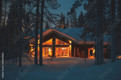 A night view of cozy wooden scandinavian cabin cottage chalet house covered in s Fototapet
