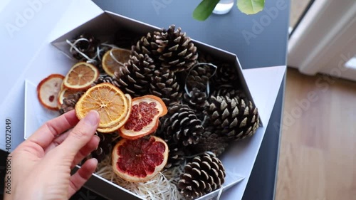 a box of pine cones and dried orange and grapefruit slices in a hand for diy projects, gift wrapping and beautiful eco Christmas decorations like wreaths