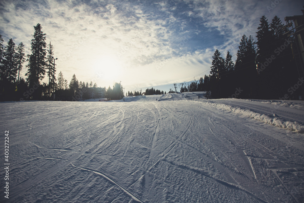 Beautiful cold mountain view of ski resort, sunny winter day with slope, piste and ski lift, with group of mountain downhill skiers and snowboarders Beautiful cold mountain view of ski resort, sunny winter day with slope, piste and ski lift, with group of mountain downhill skiers and snowboarders
