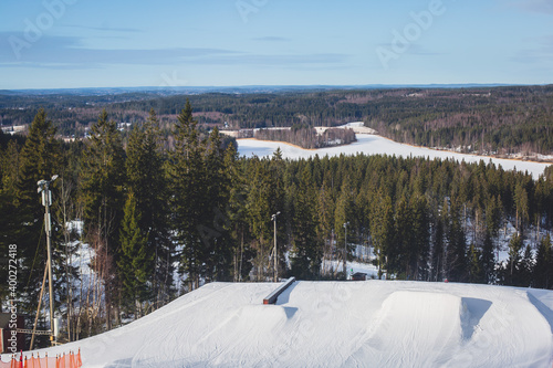Beautiful cold mountain view of ski resort, sunny winter day with slope, piste and ski lift, with group of mountain downhill skiers and snowboarders © tsuguliev