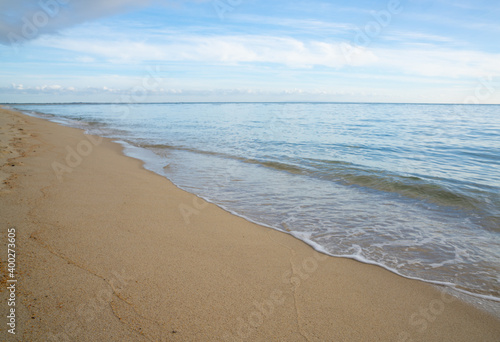 horizontal background of gentle waves on a golden sandy tropical beach photo