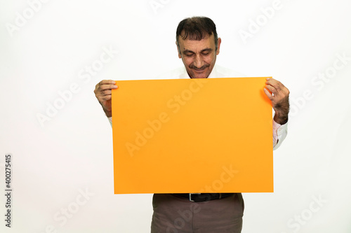 Man holding an orange banner in his hand. It can be written on. She is dressed in a white shirt and fabric pants. Isolated image white background.