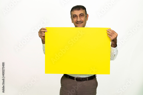 Man holding a yellow banner in his hand. It can be written on. She is dressed in a white shirt and fabric pants. Isolated image white background.