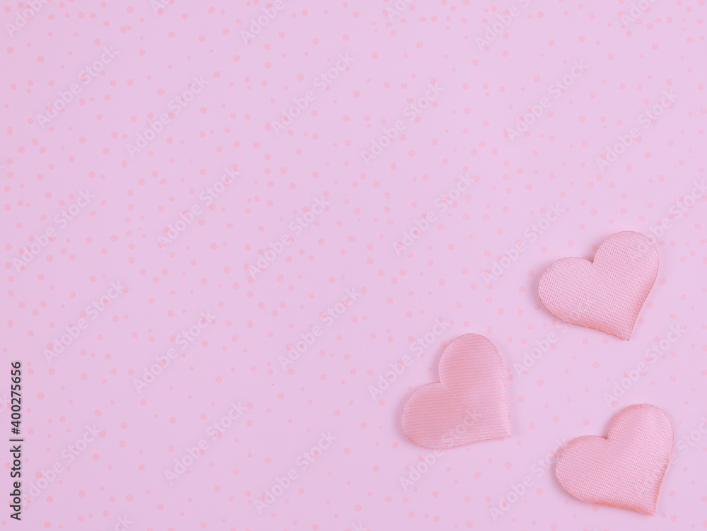 pink hearts on pink background.
Three pink hearts on the right on a pink abstract background with a place for text on the left, top view close-up.