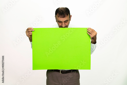 Man holding a green banner in his hand. It can be written on. She is dressed in a white shirt and fabric pants. Isolated image white background.
