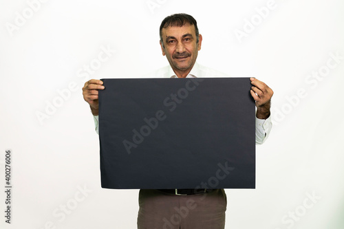 Man holding a black banner in his hand. It can be written on. She is dressed in a white shirt and fabric pants. Isolated image white background.