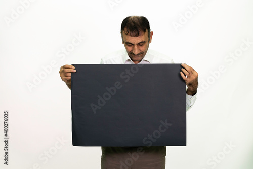 Man holding a black banner in his hand. It can be written on. She is dressed in a white shirt and fabric pants. Isolated image white background.