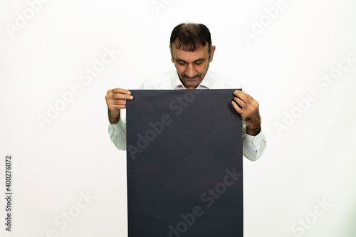 Man holding a black banner in his hand. It can be written on. She is dressed in a white shirt and fabric pants. Isolated image white background.