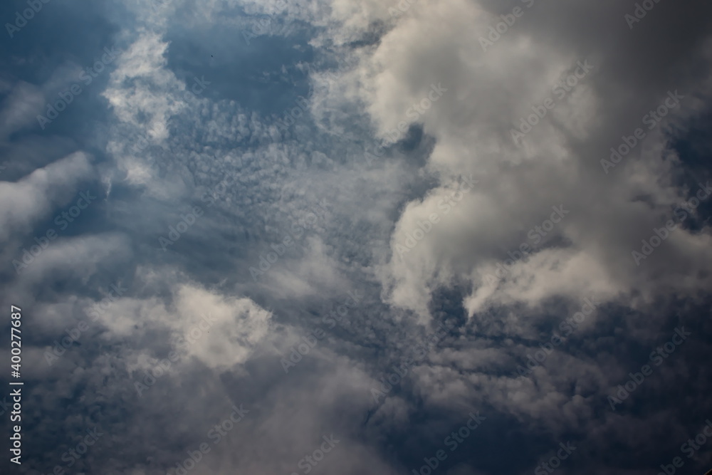 blue sky covered by a curtain of Altocumulus clouds, with cumulus clouds floating softly in the foreground.