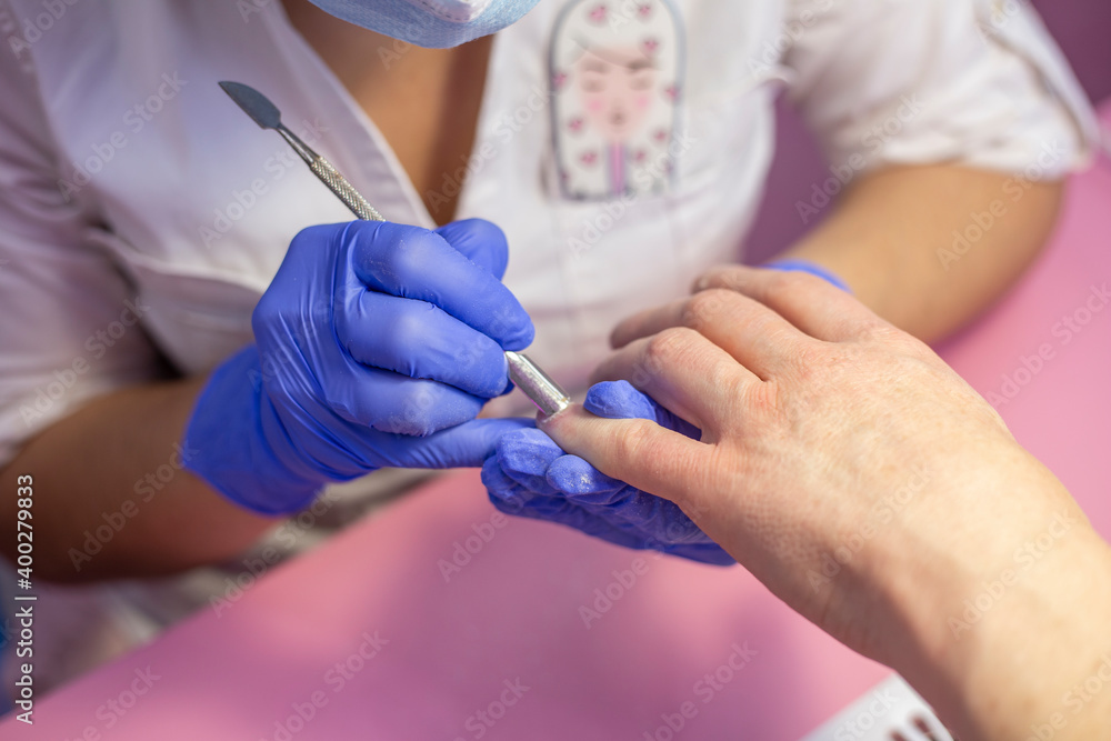 Closeup hands in gloves of a qualified manicurist doing man's nails. Men's manicure in salon