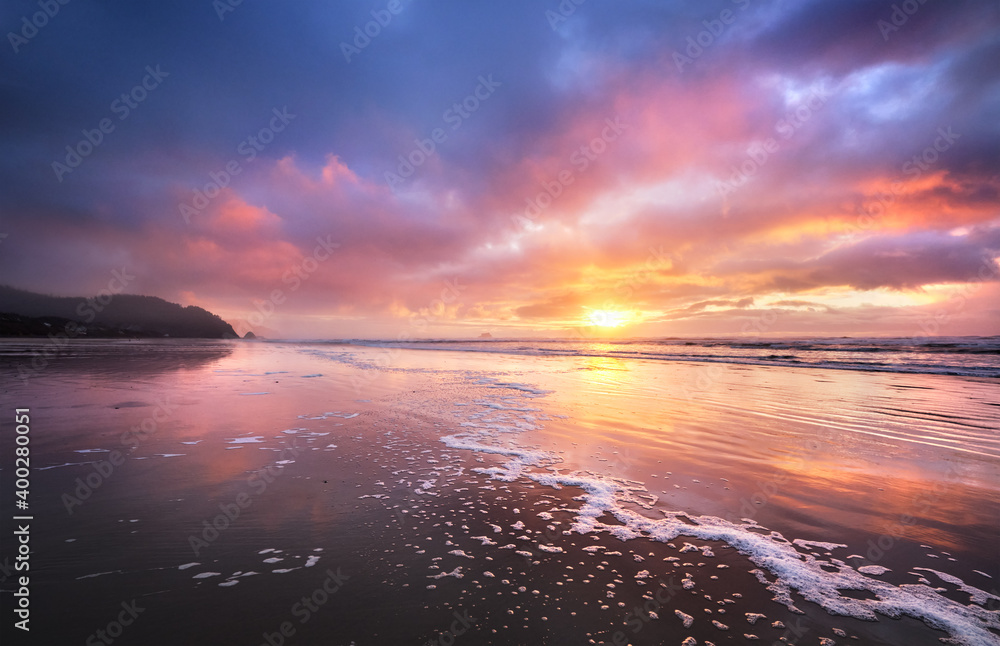 A Wintry beach in Arch Cape, Oregon with the sun going down at low tide