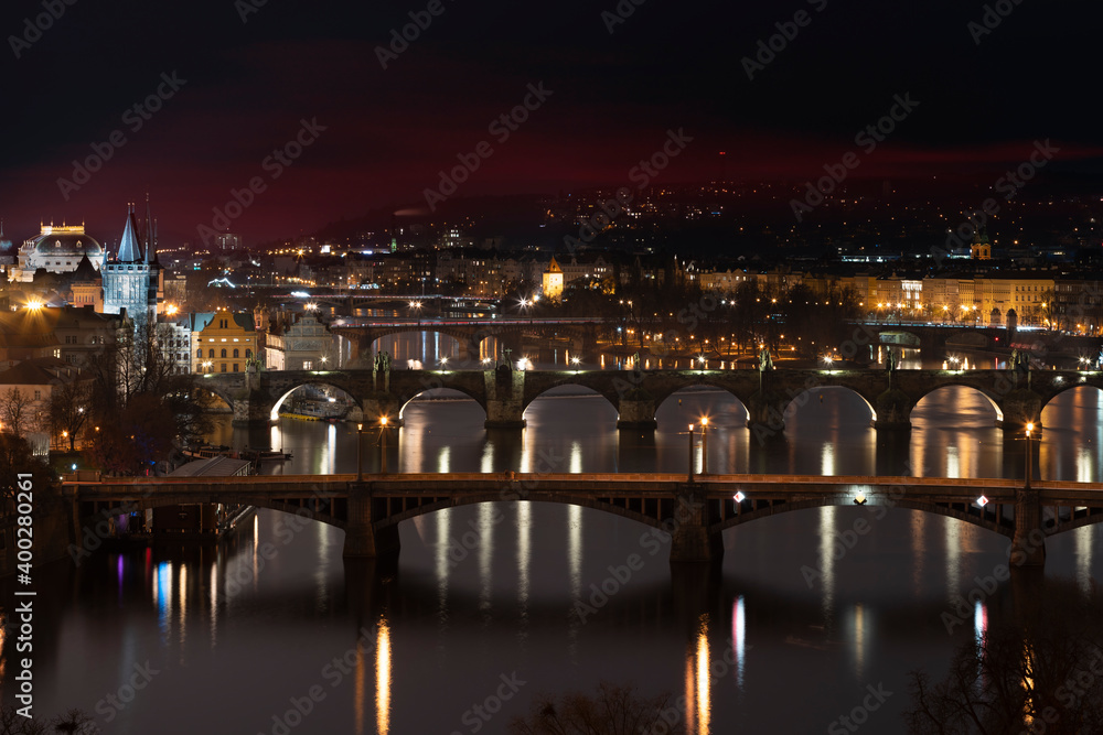 .view of the Vltava river and the bridges on it between them and the Charles Bridge and light from street lighting and the roofs of buildings in the center of Prague at night