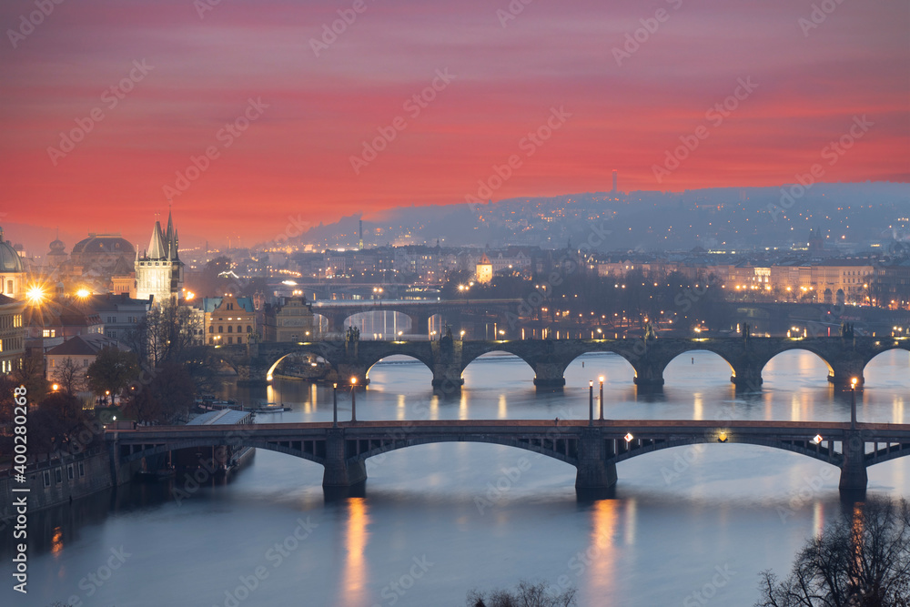 .view of the Vltava river and the bridges on it between the bridges and the Charles Bridge and the surrounding architecture and light from the street lights in the center of Prague after sunset