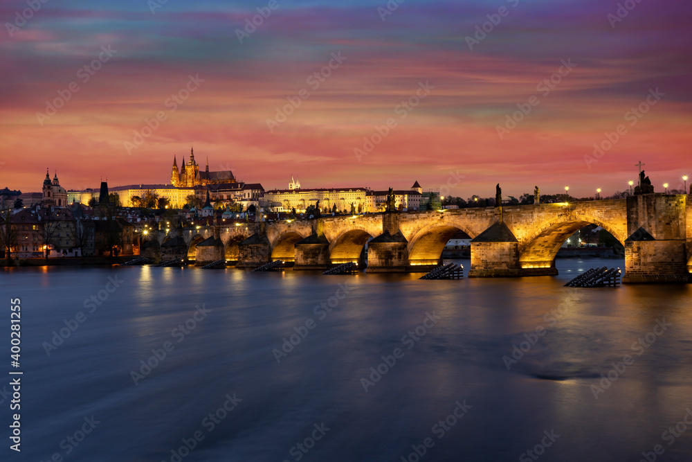 panorama prague castle and charles bridge and st. vita church lights from street lights are reflected on the surface of the vltava river in the center of prague at night in the czech republic