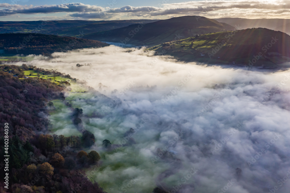 Aerial view looking down onto a trees in a beautiful, rural fog filled valley (Mid Wales)