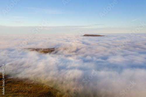 Fototapeta Naklejka Na Ścianę i Meble -  Aerial view of mountains rising above a sea of fog on a bright, sunny day