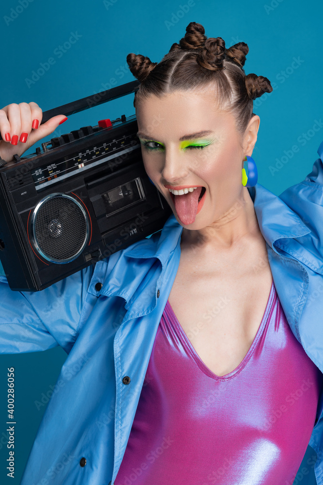 Beautiful smiling girl with stylish hair and makeup holds boombox