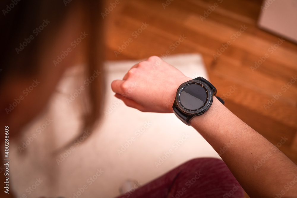 Young caucasian woman looking at the sport watch while doing exercises at home Young caucasian woman looking at the sport watch while doing exercises at home