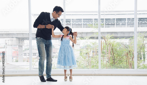 Father is teaching his little daughter to dance in the halls of the house. Happy holidays, family relationships.