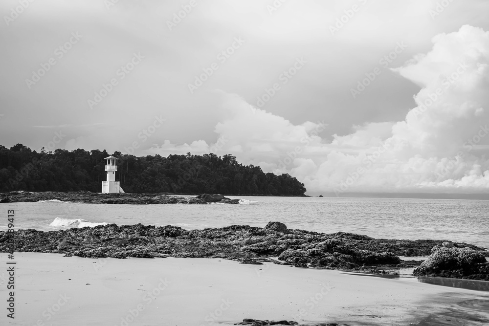 Black and white picture of sea shore with light house background.