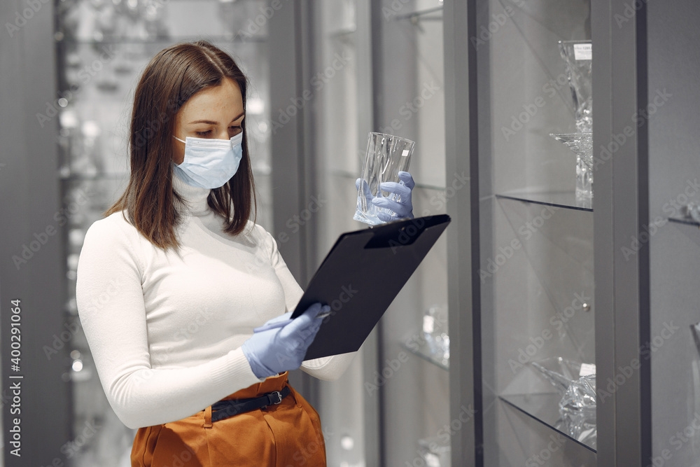 Woman examines various items of dishes. Beautiful woman shopping tableware in supermarket. Corona virus concept. Woman examines various items of dishes. Beautiful woman shopping tableware in supermarket. Corona virus concept.