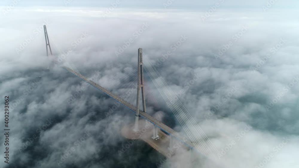 Aerial fast hyperlapse epic low fog, moving fast clouds cable-stayed Russian bridge modern scenic Vladivostok best cityscape downtown. Road traffic cars ride. Blue sea Eastern Bosphorus. Emotional Aerial fast hyperlapse epic low fog, moving fast clouds cable-stayed Russian bridge modern scenic Vladivostok best cityscape downtown. Road traffic cars ride. Blue sea Eastern Bosphorus. Emotional