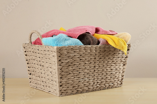 Wicker laundry basket with towels on wooden table