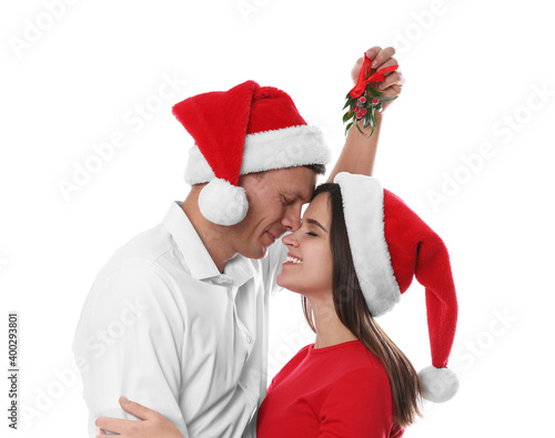 Happy couple under mistletoe bunch on white background