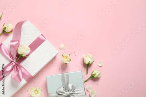 Elegant gift boxes and beautiful flowers on pink background, flat lay. Space for text © New Africa