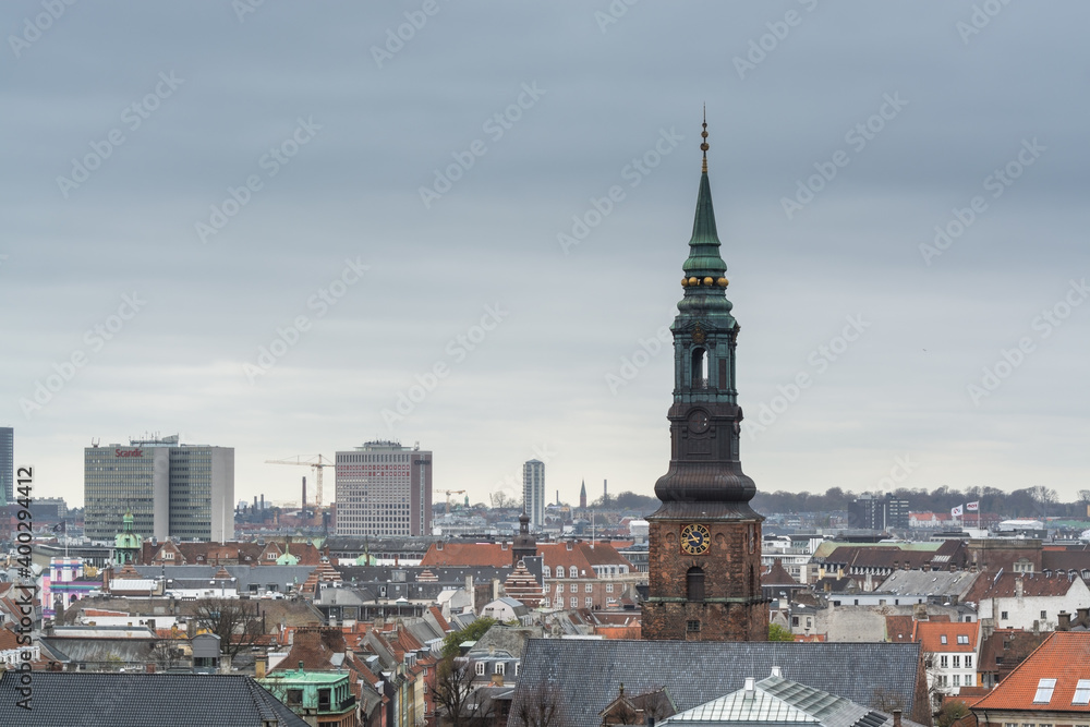 Aerial view of Copenhagen City from the The Round Tower (Rundetaarn) in rainy misty day with cloudy sky and building of St. Peter's Church bell tower