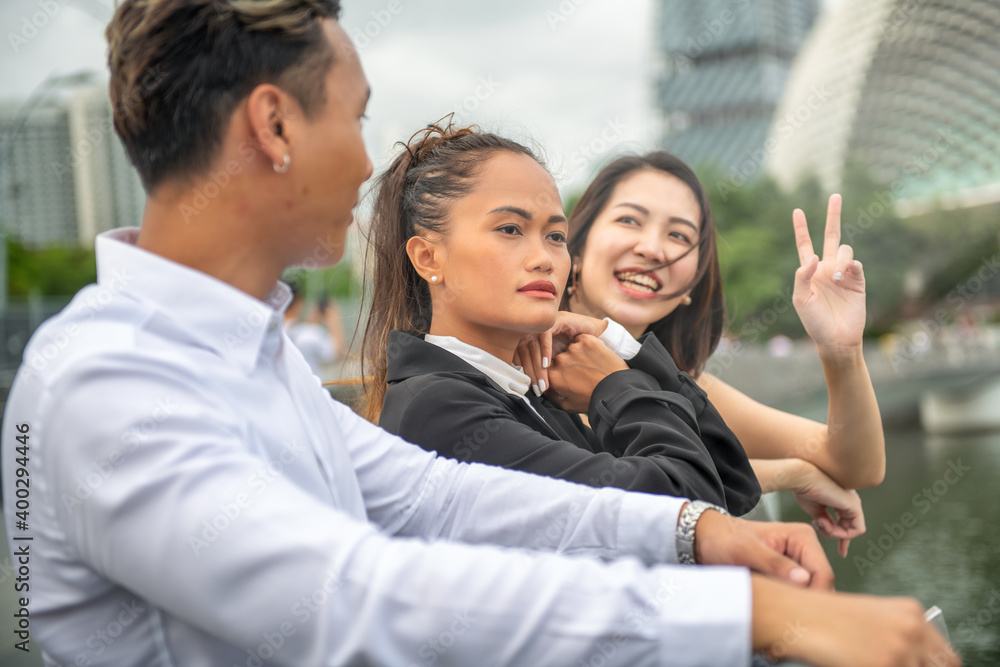 Three asian young friends standing outdoor looking at the city skyline. Street life of two girls and one boy Three asian young friends standing outdoor looking at the city skyline. Street life of two girls and one boy