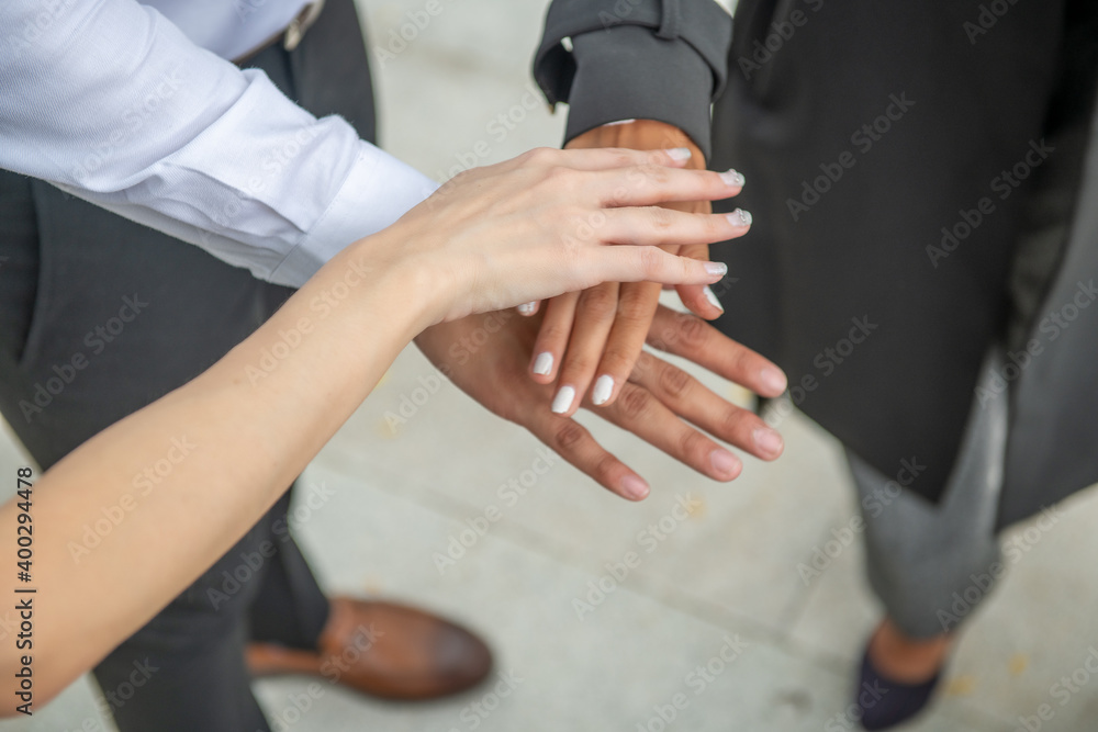 Business meeting. One man and two women stacking their hands