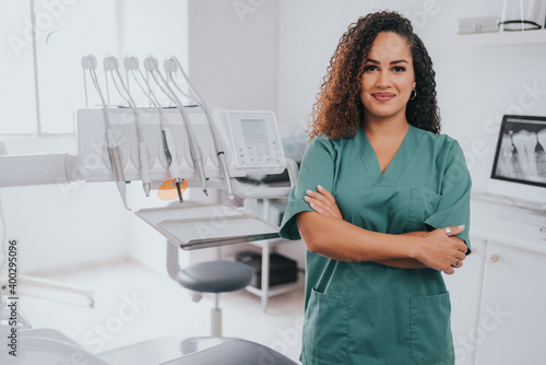Young blond Caucasian female opening her mouth while African-American ethnic dentist in white latex gloves check condition of her teeth (focus on dentist)