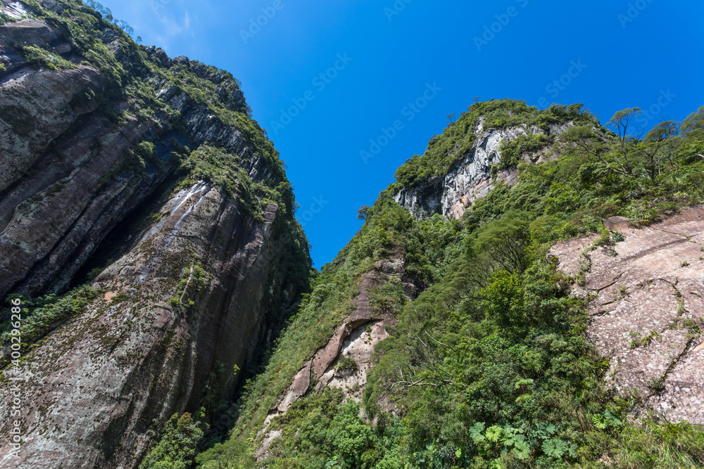 Montanha de rocha com floresta e céu azul.