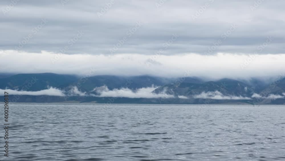 Morning lake after rain, with blue water and mountains in dramatic low clouds and fog. Cloudy sky in the morning after a night thunderstorm at Lake Baikal. A seagull is flying by.
Morning lake after rain, with blue water and mountains in dramatic low clouds and fog. Cloudy sky in the morning after a night thunderstorm at Lake Baikal. A seagull is flying by.