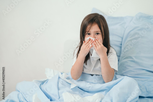 The little girl caught a cold. Children sneeze into a handkerchief. The child is ill and is being treated at home. Seasonal colds in children