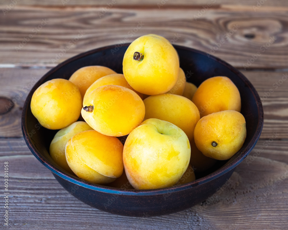 Ripe apricots in a deep cup on a wooden background
