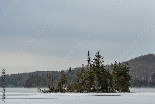Mist rising around an island and partially frozen lake landscape