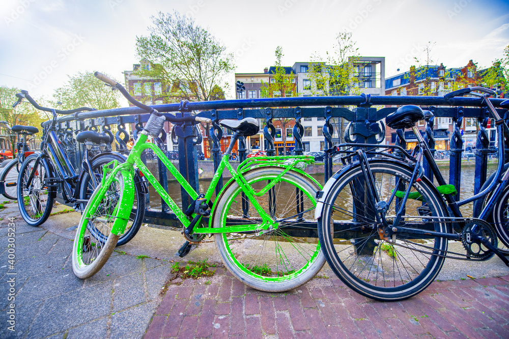 AMSTERDAM, THE NETHERLANDS - APRIL 25, 2015: The life of canals and streets. Bikes parked along the bridge