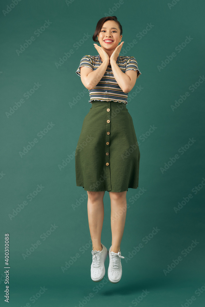 Happy young woman jumping on green background Happy young woman jumping on green background