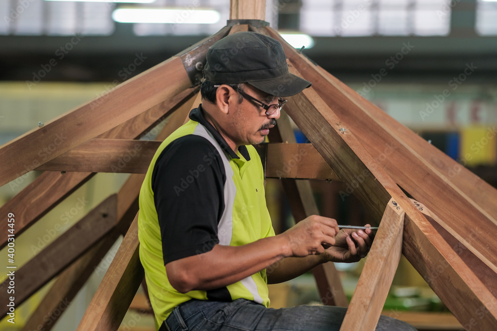 Carpenter using bolt and nut in installation of roof rafters on a new gazebo construction project . Carpenter using bolt and nut in installation of roof rafters on a new gazebo construction project .