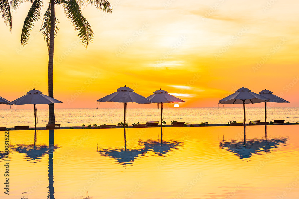 Umbrella and deck chair around outdoor swimming pool in hotel resort