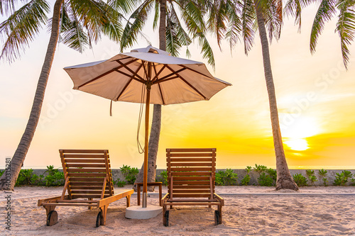Fototapeta Naklejka Na Ścianę i Meble -  Umbrella and deck chair on tropical beach sea ocean at sunset or sunrise time