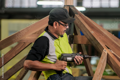 Carpenter using bolt and nut in installation of roof rafters on a new gazebo construction project . © azami