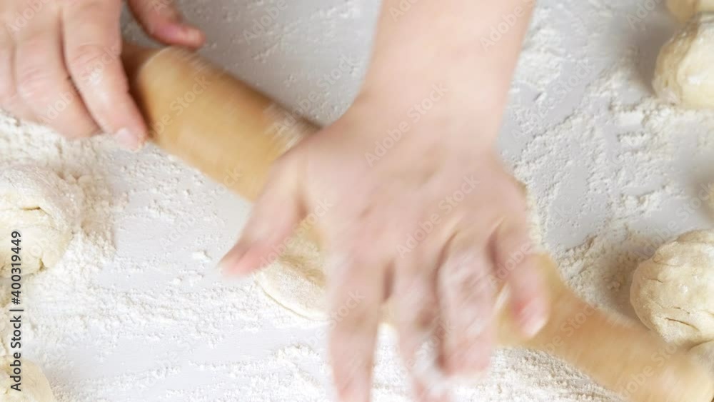 Makes dough pies.Rolls out the dough with a rolling pin.Flour on a white table. Makes dough pies.Rolls out the dough with a rolling pin.Flour on a white table.